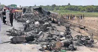  ?? [AP PHOTOS] ?? Pakistan army soldiers stand guard while rescue workers examine the site of an oil tanker explosion at a highway near Bahawalpur, Pakistan, Sunday. An overturned oil tanker burst into flames in Pakistan on Sunday, killing more than one hundred people who had rushed to the scene of the highway accident to gather leaking fuel, an official said.