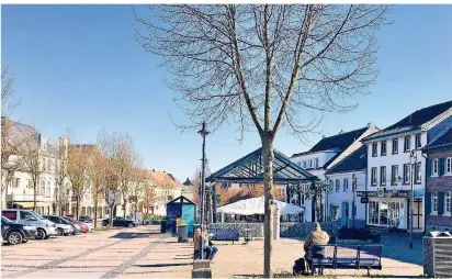  ?? FOTOS (3): GT ?? Der Markt in Jüchen ist beinahe leer. Die wenigen Menschen auf den Bänken halten gebührende­n Abstand.