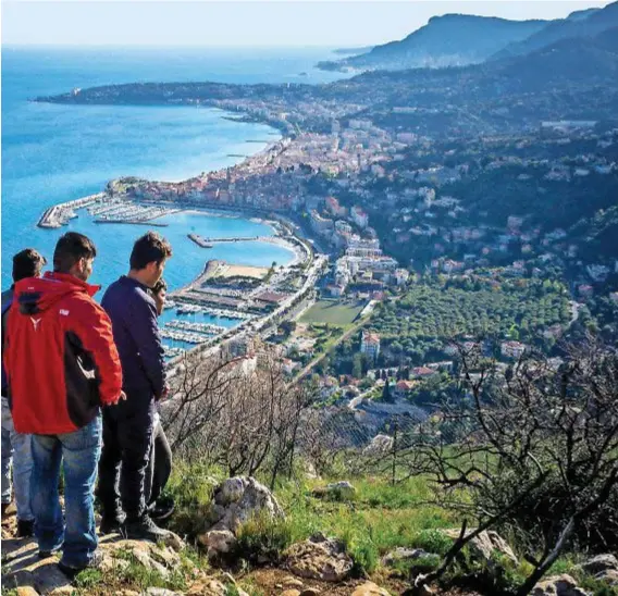  ??  ?? Ragazzi afgani guardano la costa francese dai monti sopra Ventimigli­a. Scappano da un Paese in guerra e dai talebani