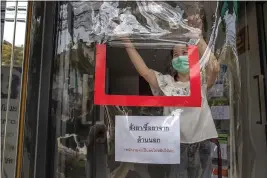  ?? GEMUNU AMARASINGH­E — THE ASSOCIATED PRESS ?? A pharmacist opens a service window through a plastic sheet covering the entrance to help practice social distancing in Bangkok, Thailand, Thursday. A state of emergency has been declared in the country to allow the government to impose stricter measures to control the coronaviru­s that has infected hundreds of people in the region. The new coronaviru­s causes mild or moderate symptoms for most people, but for some, especially older adults and people with existing health problems, it can cause more severe illness or death.