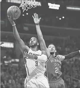 ?? Mark J. Terrill Associated Press ?? CLIPPERS POINT GUARD Chris Paul, laying the ball up in front of Andre Roberson, did not return to the game after spraining his left thumb in second quarter.