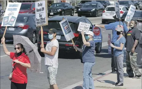  ?? Myung J. Chun Los Angeles Times ?? POSTAL WORKERS and customers rally Tuesday in front of the Beverly Boulevard Bicentenni­al Station post office in Los Angeles.