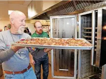  ??  ?? Cecil Johnson, a member of the Rother Men of St. Andrew Catholic Church, pulls a tray of baked chicken from the oven on April 15 at the Moore church.