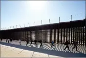  ?? GREGORY BULL — THE ASSOCIATED PRESS FILE ?? A group of people, including many from China, walk along the wall after crossing the border with Mexico to seek asylum on Oct. 24 near Jacumba.