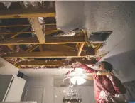  ?? Brett Coomer / Staff photograph­er ?? Hannah Siqueiros clears insulation from a damaged ceiling after a broken pipe above the kitchen was repaired.