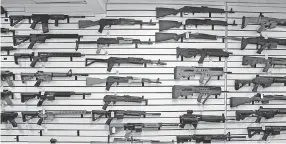  ??  ?? Semi- automatic rifles line a wall in a gun shop in Lynnwood, Wash. Gun- rights supporters say the best answer to a bad guy with a gun is a good guy with a gun. Gun- control advocates, meanwhile, say it is too easy to get a weapon in the U. S. ELAINE THOMPSON/ AP