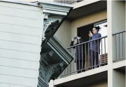  ??  ?? Neighbors take photos as the Victorian house, built in 1882, passes their balcony as it is moved from its original site on Franklin Street.