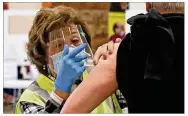  ?? BILL LACKEY/STAFF ?? Patricia Hart, a volunteer at the Clark County Combined Health District’s COVID vaccine distributi­on center, gives a Clark County resident his shot Tuesday.