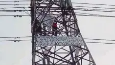  ??  ?? AGUSTINUS mengibarka­n sepanduk ketika berada di atas menara elektrik bervoltan tinggi di Jakarta Utara kelmarin. - Agensi