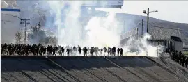  ?? DAVID GUZMAN / EFE ?? Border police use tear gas Sunday to prevent people from crossing the U.S.-Mexico border in Tijuana, Mexico, after a group of migrants deviated from plans to cross at the San Ysidro (U.S.) gateway to try to cross at other points.