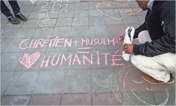  ?? AURORE BELOT, AFP/GETTY IMAGES ?? A man writes on the ground, “Christian and Muslim equals humanity” in a tribute to victims at a makeshift memorial in front of the stock exchange at the Place de la Bourse in Brussels on Tuesday.