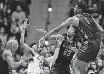  ?? Jessica Hill / Associated Press ?? A blocked shot by UH's Chris Harris Jr., right, sends the basketball and UConn’s Tyler Polley flying in the opposite direction Thursday night. The Cougars improved to 24-1 with the win.