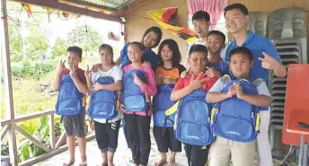  ??  ?? Lau (right) and his team pose with the children who were happy upon receiving new school bags and stationery.