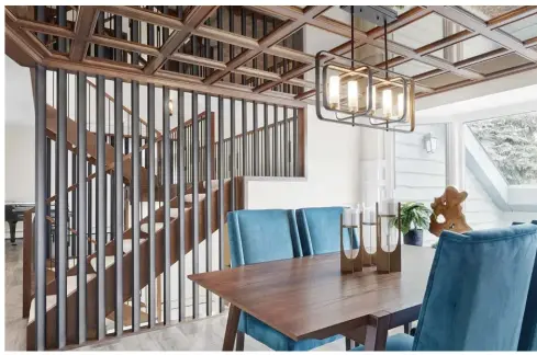  ??  ?? Displaying innovative room transition­s, black matte wrought iron spindles are set at a 45degree angle, bordering dining room charms where a dropped grid, oak ceiling is stained to match staircase features.