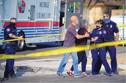  ?? ADOLPHE PIERRE-LOUIS/JOURNAL ?? Albuquerqu­e police officers talk to the relatives of a homicide victim April 11 on Wyoming NE near Constituti­on.