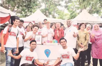  ?? — Bernama photo ?? Lee (standing, centre) poses with volunteers after officiatin­g at the World AIDS Day celebratio­n at Kinta River Walk. Also present are Perak Health Minister Datuk Dr Ding Lay Ming (standing, second right) and Malaysia AIDS Council president Bakhtiar Talhah (standing, fourth right).