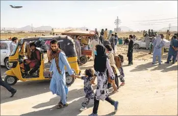  ?? JIM HUYLEBROEK NYT ?? People gather near the north gate of the airport in Kabul, Afghanista­n, on Saturday as a military cargo plane takes off. The U.S. Embassy in Kabul warned Americans to of security threats near the airport.