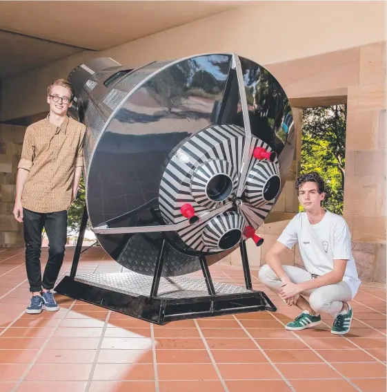  ?? Picture: JERAD WILLIAMS ?? Bond University students, George Cary and Haydn Shaw, standing next to 700kg replica space capsule (from Gilmour Space Technologi­es)