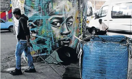  ?? / KABELO MOKOENA ?? A man pulls a trolley as he makes his way to a recycling place next to Newtown Junction, Johannesbu­rg. Some unemployed people survive by collecting and selling recyclable material.