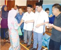  ??  ?? SADDI menyampaik­an bantuan zakat sambil dibantu Ketua Amil Bandar Sandakan Awang Staraia Abdullah.