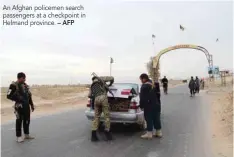  ?? — AFP ?? An Afghan policemen search passengers at a checkpoint in Helmand province.
