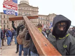  ?? RYAN GARZA/USA TODAY NETWORK ?? Supporters of then-President Donald Trump raise a red cedar cross as hundreds gathered for a rally Jan. 6 outside Michigan’s State Capitol in Lansing.