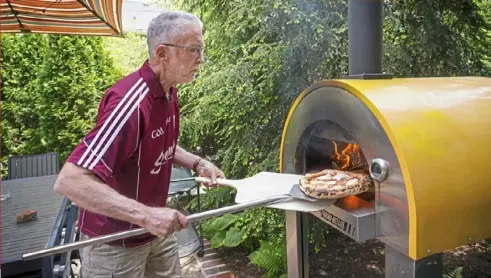  ?? Steve Mellon/Post-Gazette ?? Mike Murphy, of Edgeworth, removes a Margherita pizza from his outdoor pizza oven.