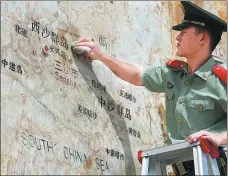 ?? WEI TAOZE / FOR CHINA DAILY ?? A guard cleans a stone map on Yongxing Island that indicates the locations of various districts of Sansha city, Hainan.