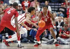  ?? Associated Press ?? Hog penned: Oklahoma guard Milos Uzan, center, and Arkansas guard Khalif Battle (0) go for the ball during the first half Saturday in Tulsa, Okla.