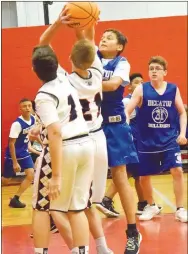  ?? Westside Eagle Observer/MIKE ECKELS ?? Giovanni Puga (second from right) gets a hand on the ball, preventing a Knight player from putting up a shot during the Decatur-St. Vincent Catholic Academy junior high basketball contest in Fayettevil­le.