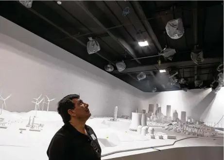  ?? Brett Coomer photos / Houston Chronicle ?? Esteban Gonzalez examines the 2,500-square-foot “Energy City” exhibit in the new Wiess Energy Hall. Once completed, the model landscape will represent Houston, the Gulf coastal water and part of Southeast Texas and will be illuminate­d by a series of...