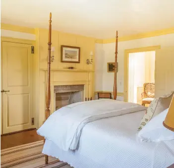  ??  ?? RIGHT A guest room on the second floor of the 18thcentur­y house has cheerful yellow woodwork and a reproducti­on flame-maple, pencil-post bed—a fine reproducti­on. The paneled wall and granite fireplace are original.