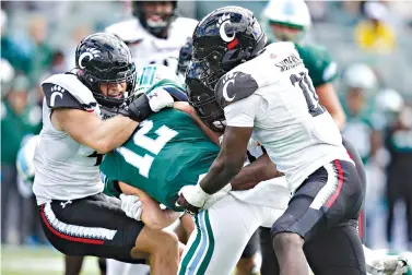  ?? AP Photo/Gerald Herbert ?? ■ Tulane quarterbac­k Kai Horton (12) is brought down by Cincinnati linebacker Joel Dublanko and defensive lineman Myjai Sanders (21) during the second half of an NCAA football game Saturday in New Orleans. Cincinnati won 31-12.