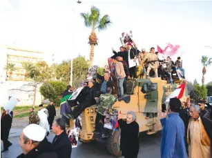  ?? (Reuters) ?? SUPPORTERS OF the Libyan National Army (LNA) commanded by Gen. Khalifa Haftar, celebrate atop a Turkish military vehicle in Benghazi, in January.