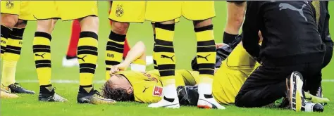  ?? DPA-BILD: SEEGER ?? Der auf dem Boden liegende Marcel Schmelzer zieht sich aufgrund der Schmerzen das Trikot ins Gesicht.