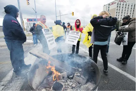  ?? FRANK GUNN/THE CANADIAN PRESS ?? Striking Canada Post workers walk the picket line in Mississaug­a, Ont., on Tuesday. Morton Mitchnick has been appointed to join a team of federal mediators in talks with Canada Post and the Canadian Union of Postal Workers over contract demands.