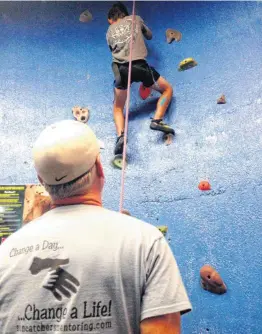  ??  ?? Joey Shaw, founder of Soncatcher­s Mentoring, watches a youth on a climbing wall during a mentoring outing.