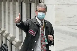  ?? MARK LENNIHAN — THE ASSOCIATED PRESS ?? Trader Daniel Krieger signals a thumbs-up as he arrives at the New York Stock Exchange where the trading floor reopened Tuesday.