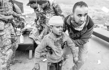  ??  ?? A boy injured in a mortar attack walking toward an ambulance after being treated by medics in a field clinic as Iraqi forces battle with Islamic State militants, in western Mosul. — Reuters photo