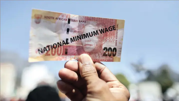  ?? PICTURE: NIC BOTHMA / EPA ?? OVERDUE: A protester holds up a fake R200 note with the words ‘national minimum wage’ printed on it during a Cosatu protest in Cape Town in 2015. ‘Finally, for the first time since the call was made in 1955 by our forebears when they drafted the...