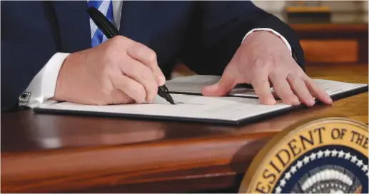  ?? (Jonathan Ernst/Reuters) ?? US PRESIDENT Donald Trump signs a proclamati­on declaring his intention to withdraw from the JCPOA Iran nuclear agreement in the White House last month.