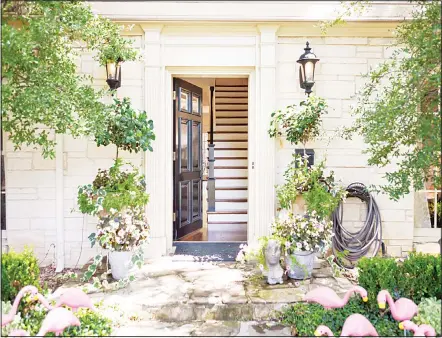  ?? (AP) ?? This undated photo provided by Abbe Fenimore shows the delicate leaves and flowers of potted flowering plants which creates a perfect balance with the
architectu­ral moulding and a dramatic black front door at this entryway designed by Fenimore of...