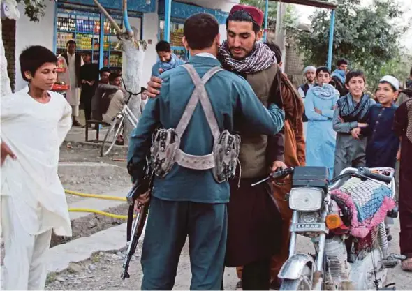  ?? EPA PIC ?? A Taliban militant suspect greeting a police officer in Kunduz, Afghanista­n, on Friday.