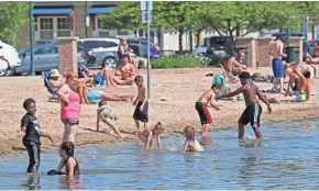  ?? MICHAEL SEARS / MILWAUKEE JOURNAL SENTINEL ?? Children frolic in Pewaukee Lake as parents sit on the beach and enjoy the sun Wednesday.