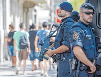  ?? FOTO: DPA ?? Polizisten stehen schwer bewaffnet am Freitag auf der Flaniermei­le Las Ramblas in Barcelona.