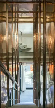  ??  ?? RIGHT: The house is on three levels. The walls surroundin­g the staircase from the ground floor to the middle level are covered in copper. The staircase from the middle level to the kitchen at the top is made of steel