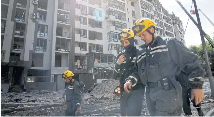  ?? REUTERS ?? Rescue workers walk outside a residentia­l building damaged by a Russian missile strike in Kyiv yesterday.