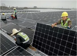  ?? PHOTO: KEVIN FRAYER/GETTY IMAGES ?? Solar power prices are dropping fast. Here Chinese workers install a floating field of panels in a heartland coal area.