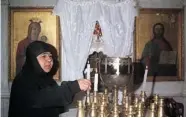  ?? LOUAI BESHARA/ GETTY IMAGES ?? A Syrian nun lights candles inside the historical church of Mar Takla in the village of Maalula.