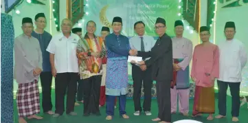  ??  ?? Sharbini (fifth left) presents donation to a mosque representa­tive.